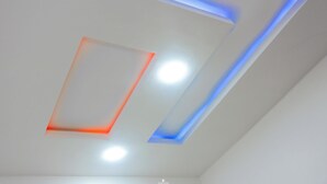 Un techo con iluminación empotrada y lámparas geométricas.