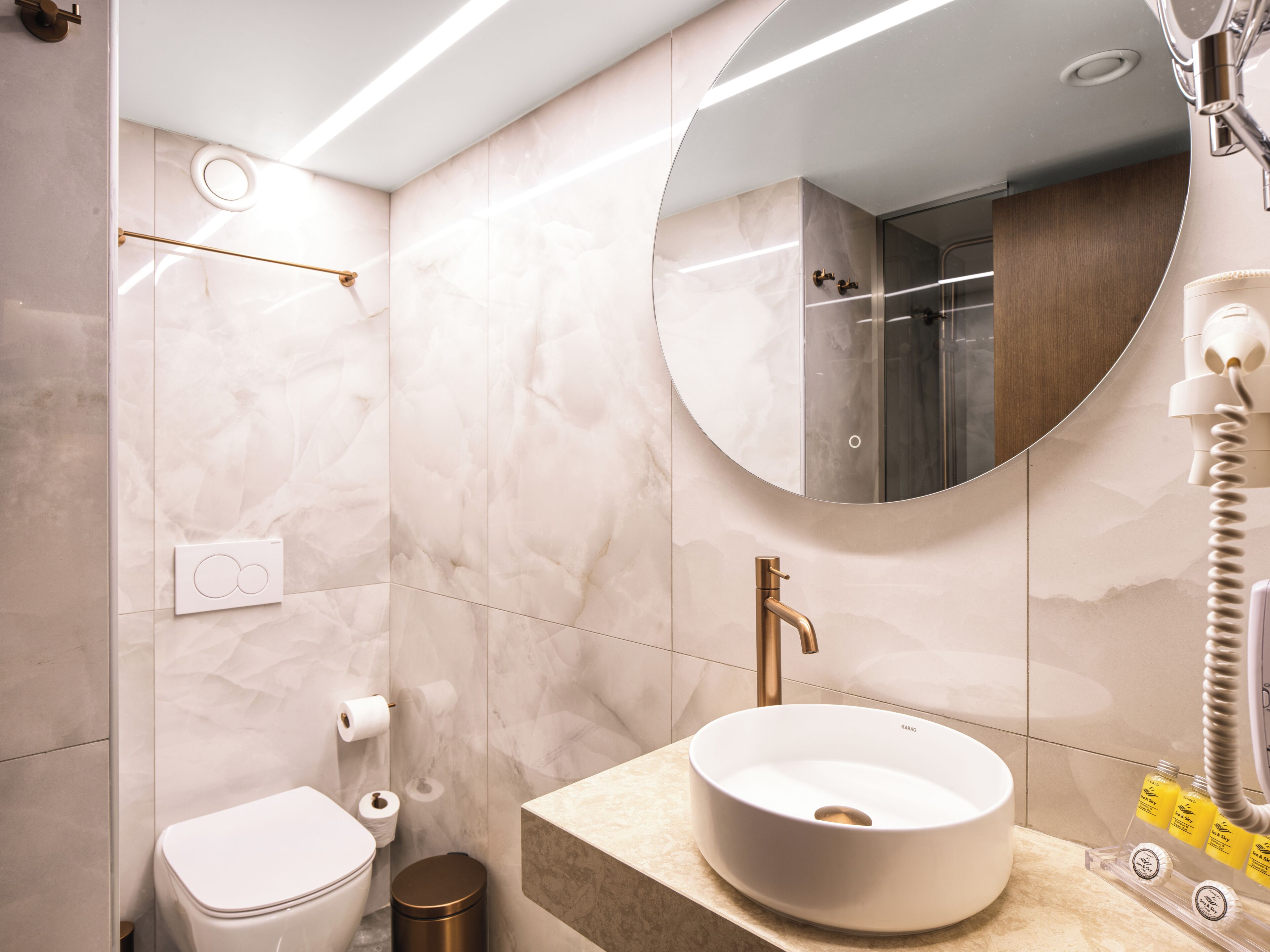 A modern bathroom with a white sink, a mirror, a toilet, and a shower.