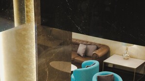 A modern lounge area with seating arrangements, a coffee table, and a lamp. - Leonardo Hotel Athens City Center (Athens)