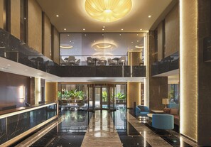 Un hall d’entrée spacieux, doté d’un sol en marbre, de coins salon et d’une entrée en verre.