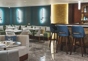 Un interno ristorante moderno con posti a sedere al bancone, divani imbottiti verdi e pavimento in marmo.