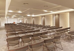 A conference room with rows of chairs, a podium, and a projector screen.