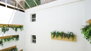 A modern interior with white walls, multiple windows, and green plants arranged in various sections. - Leonardo Hotel Athens City Center (Athens)