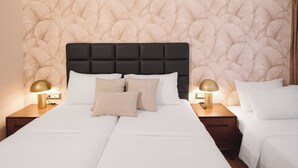 A double bed with a tufted headboard, two bedside tables with lamps, and a textured wall. - Leonardo Hotel Athens City Center (Athens)