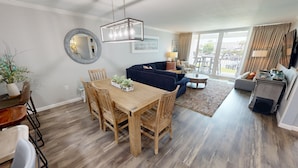 A modern living room with a dining area, a sofa, and a coffee table. - Shoreline Towers 3025 2 Bedroom Condo (Destin)