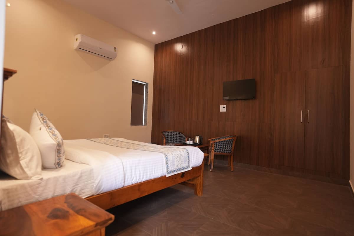 Une chambre avec un lit en bois, une chaise, un téléviseur fixé au mur et un appareil de climatisation.