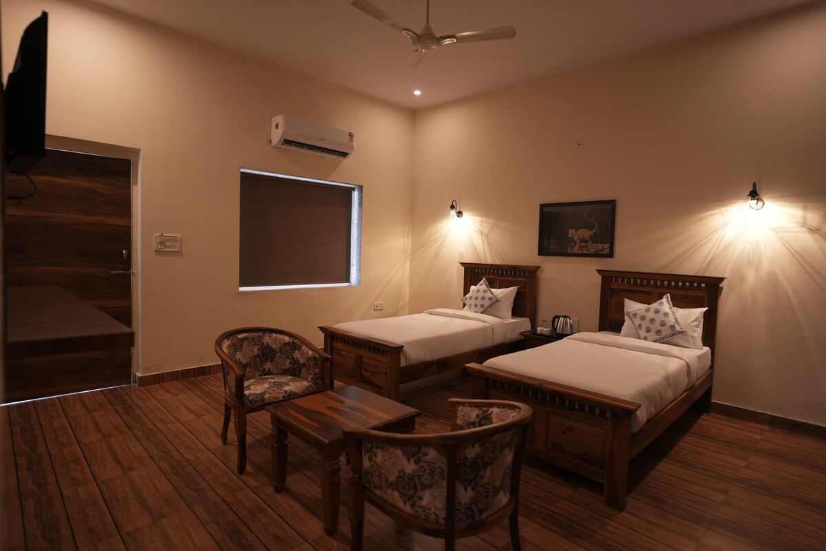 A bedroom with two beds, a wooden floor, a TV, an air conditioner, and a window.