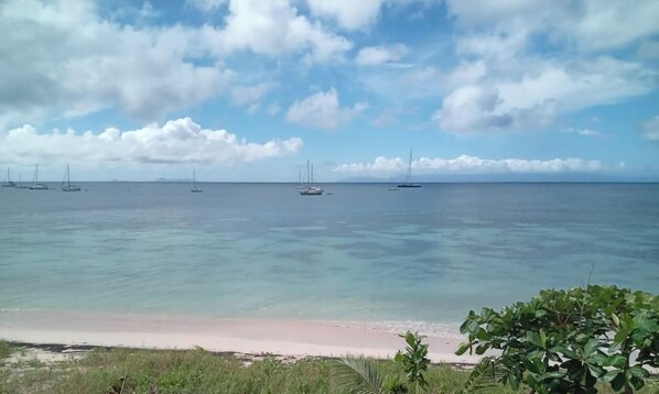 Ein Strand mit klarem Wasser und einigen Segelbooten.