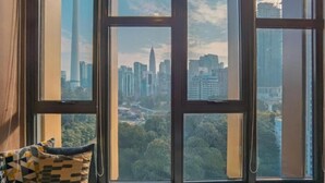 Een kamer met een groot raam met uitzicht op een stadsgezicht met hoge gebouwen en een toren.
