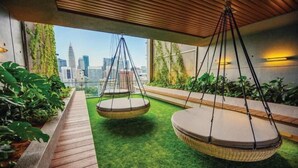 Een modern buitenverblijf met hangschommels, een houten terras en uitzicht op een stadshemelbeeld.