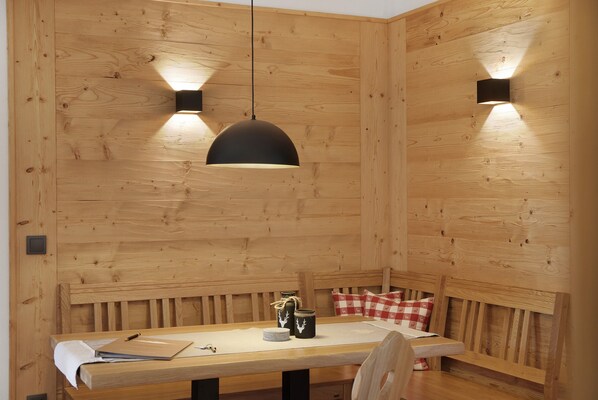 Un comedor de madera con una mesa, sillas, una lámpara colgante y un banco.