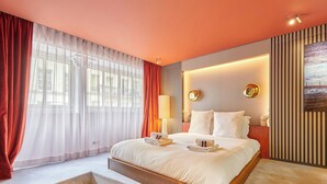 A modern hotel room with a large bed, a view of the city, and a staircase leading to the upper floor. - Sublime Apartment Beaubourg/le Marais (Paris)