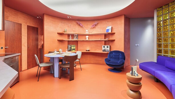 A modern living room with a round table, chairs, a blue sofa, and a unique orange floor. - Sublime Apartment Beaubourg/le Marais (Paris)