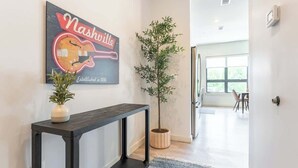 A hallway with a dark console table, a potted plant, and a neon sign reading "Nashville Established in 1806". - Music Row Magic - Pool + Gym + Downtown (Nashville)