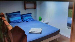 Ein Bett mit blauer Bettwäsche, Kissen und einer gefalteten weißen Decke.