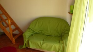 Ein Eckzimmer mit einer gepolsterten grünen Sitzbank, einer Holzleiter und einem grünen Vorhang.