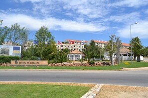 A hotel named "Quinta do Morado" with a well-maintained lawn, a gazebo, and a flag display.
