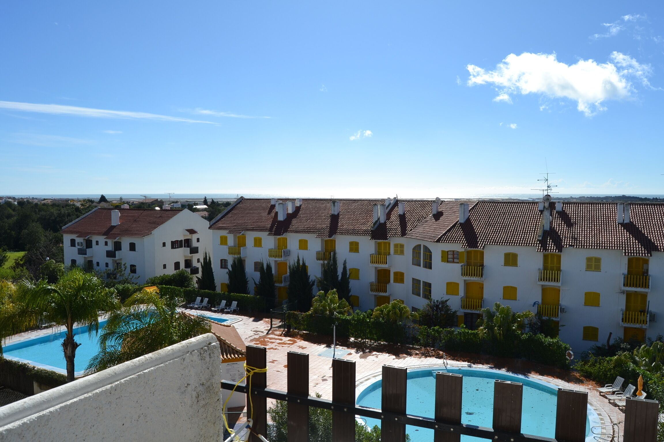 Un hôtel composé de plusieurs bâtiments blancs, doté d’une piscine et offrant une vue sur la mer.