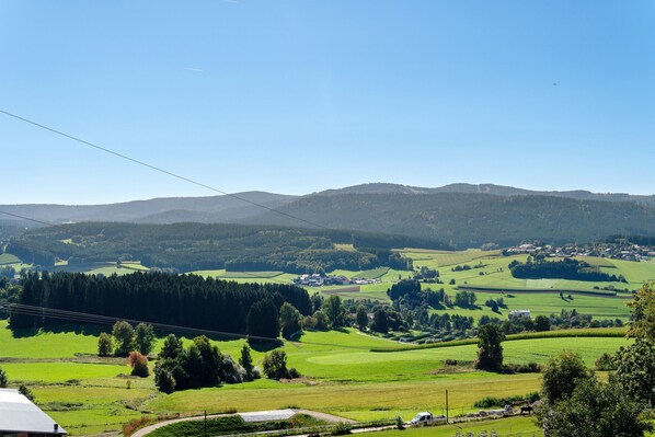 A rural landscape with rolling hills, a clear sky, and a distant village.