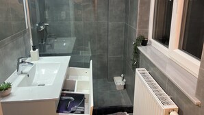 A modern bathroom with a glass shower enclosure, a white sink, and a radiator. - Located 2min from the French community, 10min from debrouckere, 7min from Dansaert (Molenbeek-Saint-Jean)
