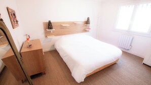 A bedroom with a wooden bed, a nightstand, a dresser, a mirror, and a window. - Maison familiale "Fin de semaine" - Swimming pool, 3 bedrooms, sleeps 6 (Capbreton)