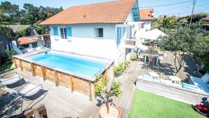A house with a swimming pool, wooden deck, and outdoor furniture. - Maison familiale "Fin de semaine" - Swimming pool, 3 bedrooms, sleeps 6 (Capbreton)