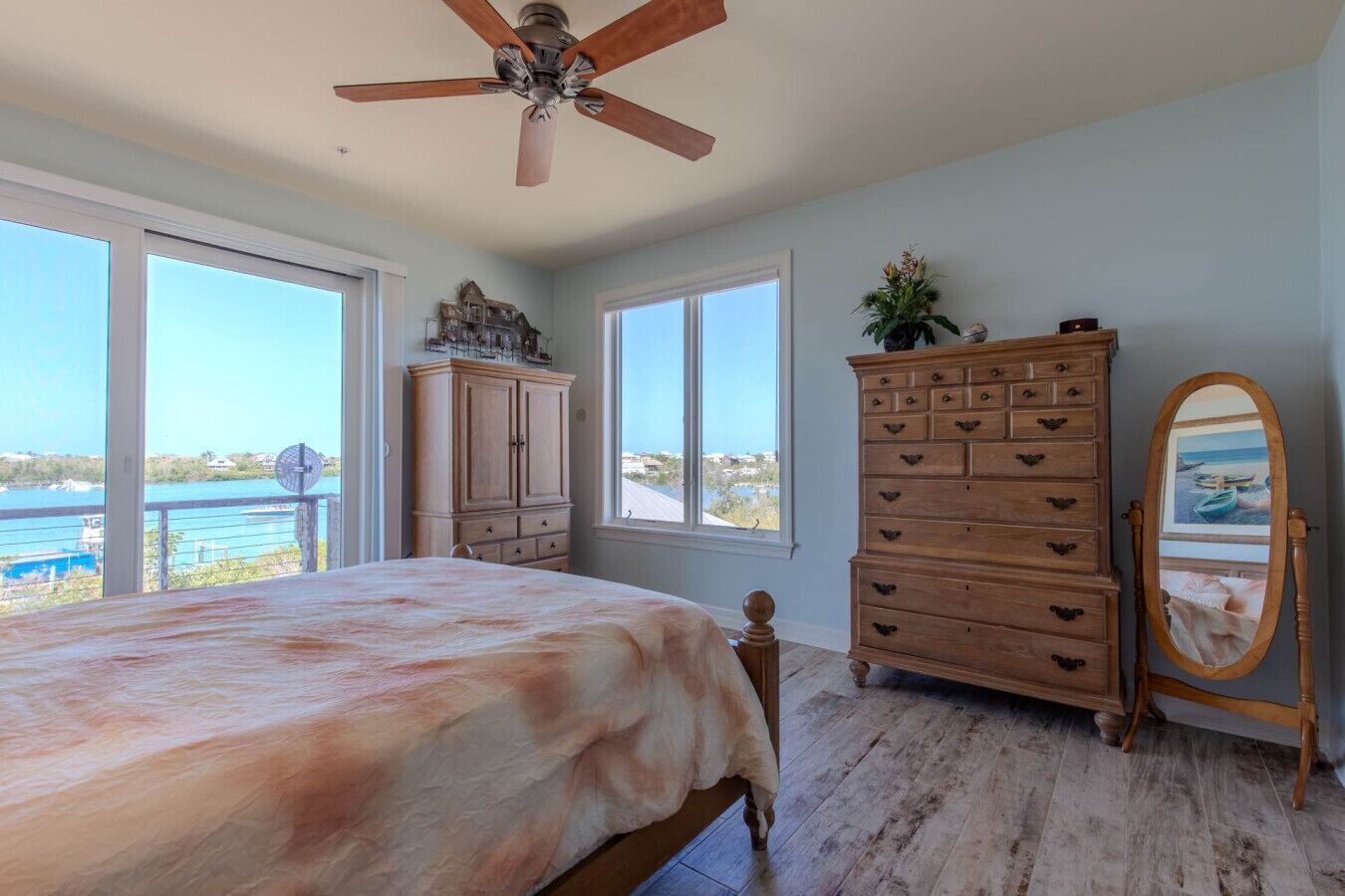 Une chambre à coucher avec un lit, une commode, un miroir et un ventilateur de plafond.