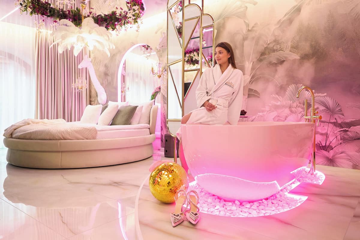 Ein luxuriöses Badezimmer mit einer großzügigen Badewanne, einer runden Sitzecke und einer Discokugel.