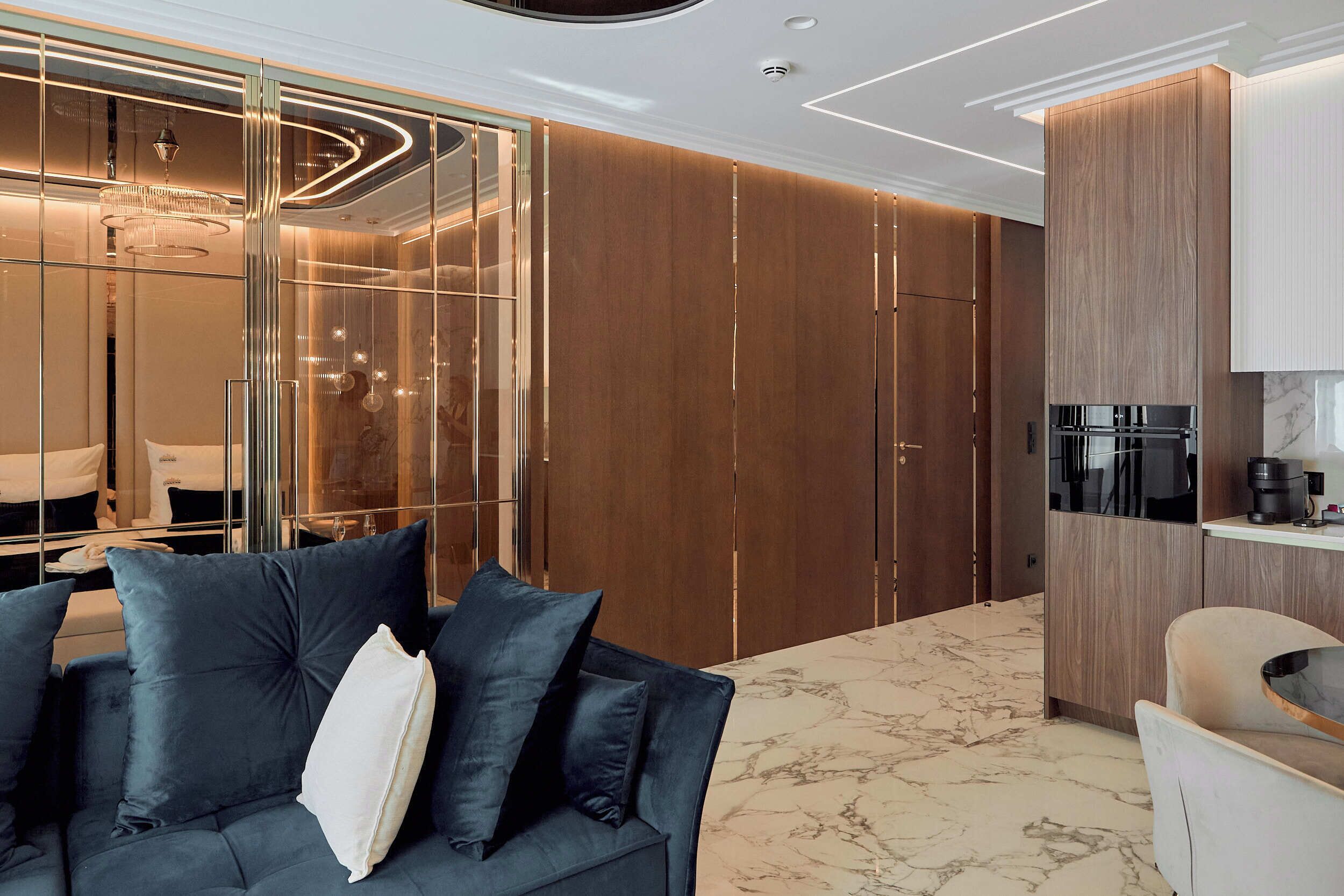 A modern living room with a dark blue sofa, wooden paneling, and a marble floor.