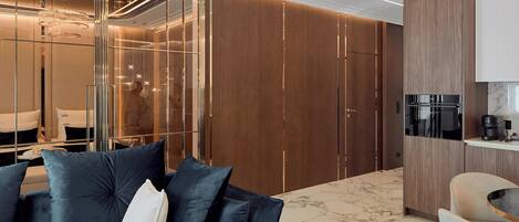 A modern living room with a dark blue sofa, wooden paneling, and a marble floor.