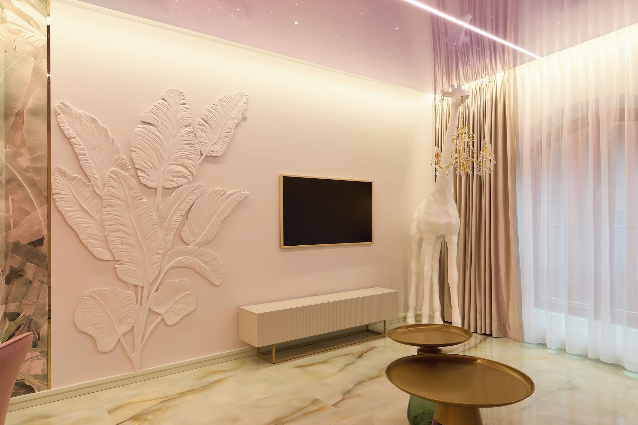 Un salon moderne avec un grand téléviseur fixé au mur, une console au design minimaliste et un élément décoratif mural représentant des feuilles.