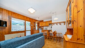 A wooden interior with a sofa, dining table, and kitchen area. - GuestHost - House of Hope (Camporosso)