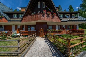 A chalet-style building with a wooden balcony, a gravel pathway, and a wooden fence. - GuestHost - House of Hope (Camporosso)