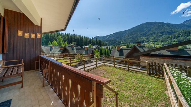 A balcony with wooden railings, a bench, and a view of a mountainous landscape with houses. - GuestHost - House of Hope (Camporosso)