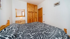 A bedroom with a bed, wooden wardrobe, dresser, and a mirror on the wall. - GuestHost - House of Hope (Camporosso)
