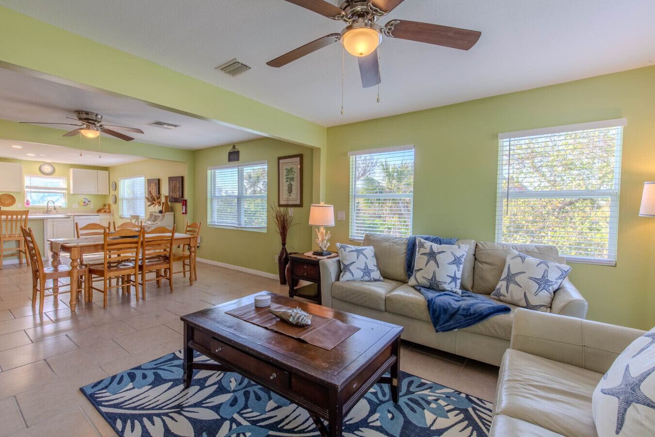 A spacious living room with a beige sofa, a wooden coffee table, and a dining area with a wooden table and chairs.