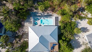 Vista aérea de un resort con piscina, sillas de descanso y una zona de terraza cubierta.