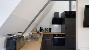 A compact kitchen with a toaster, sink, coffee maker, and oven.
