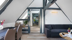 A loft-style room with a dining area, a sofa, and a wooden table.