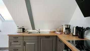 A modern kitchen with a wooden countertop, grey cabinets, a built-in oven, and a window above the sink.