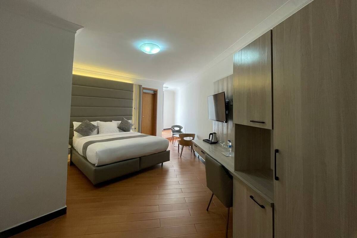 A modern hotel room with a bed, a desk, a chair, and a television.
