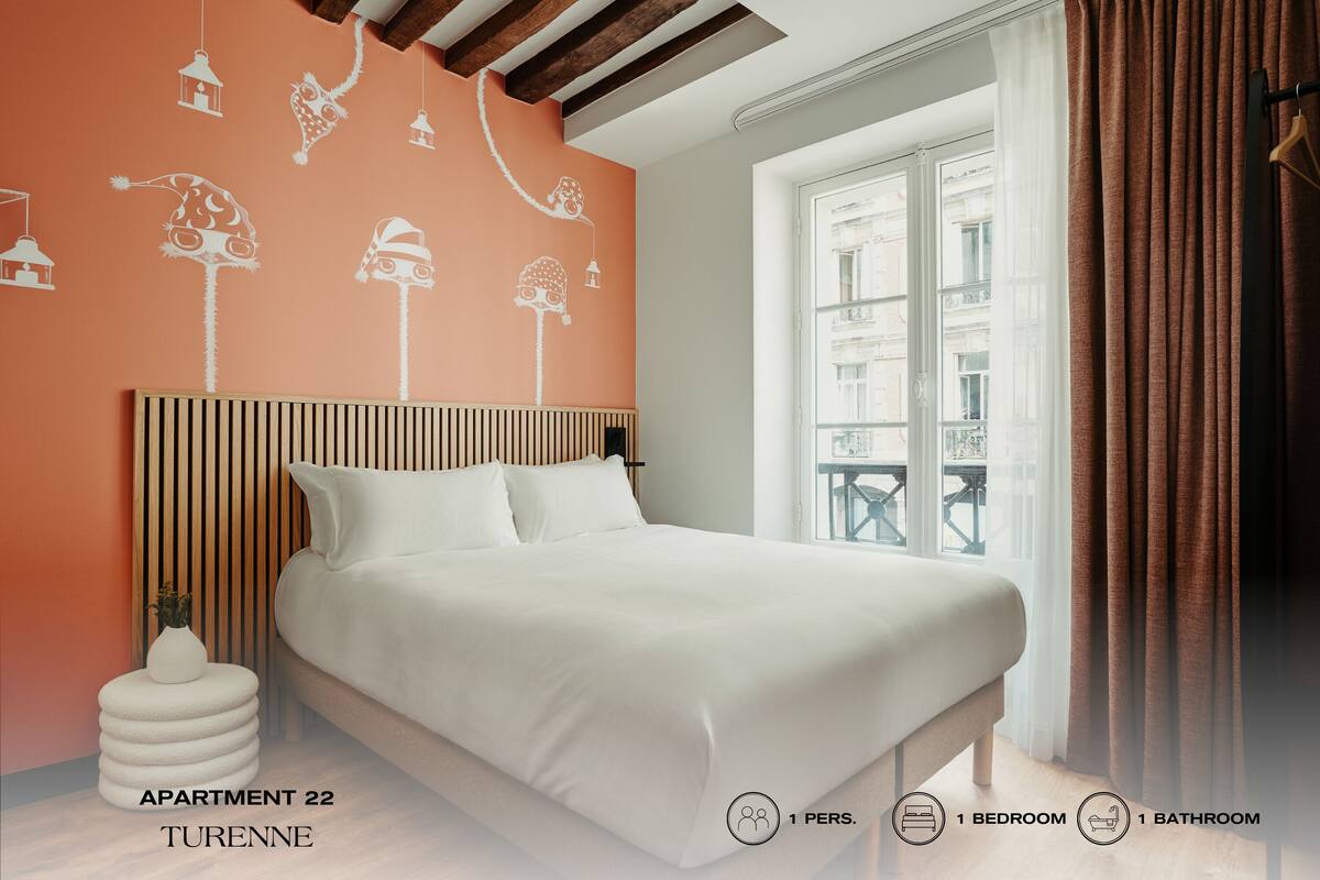 Quarto com cama, janela com cortinas e parede decorada.