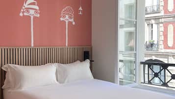 A modern hotel room with a large bed, a wooden ceiling, and a view of the city through a large window.