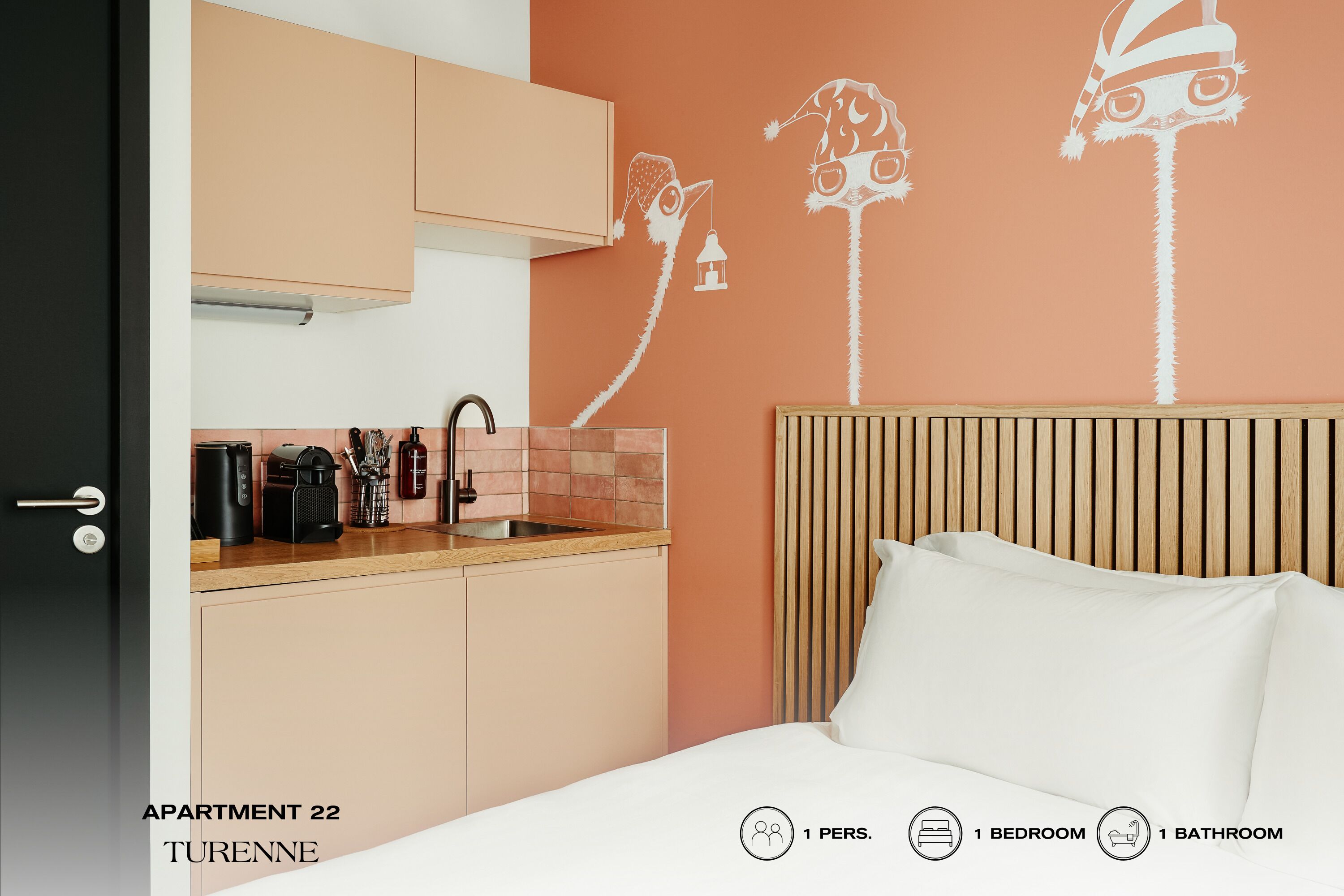 A bedroom with a bed, a wooden headboard, a nightstand, and a wall with a decorative tree design.