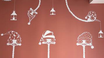 Techo con recortes de papel blanco que representan diversas decoraciones navideñas, como un gorro de Papá Noel, un reno y un muñeco de nieve, sujetos a vigas de madera.