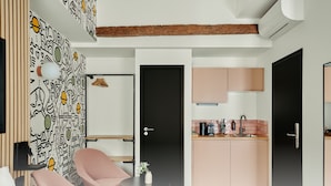 A modern kitchen with a black door, a small table with a plant, and a pink chair. - Beauquartier - Marais Turenne (Paris)
