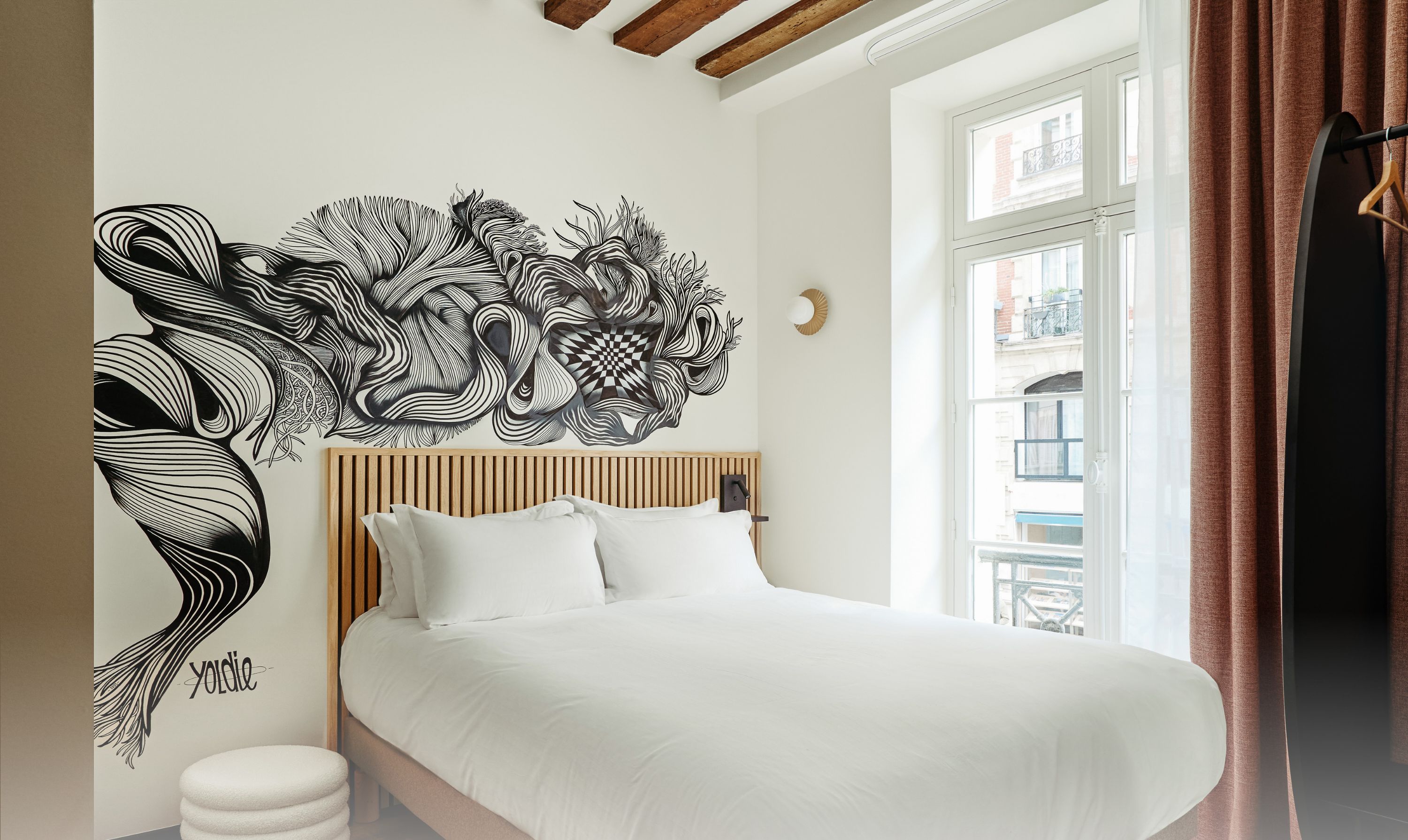 A bedroom with a bed, a wall art piece, and a window with curtains.