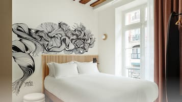 A bedroom with a bed, a wall art piece, and a window with curtains.
