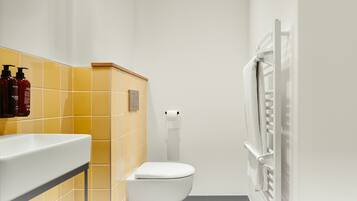 Ein modernes Badezimmer mit gelben Fliesen, einer weißen Toilette und einem Handtuchhalter.