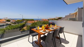 A balcony with a table set for breakfast, overlooking a cityscape and the sea. - Villa Del Pescador (Albufeira)